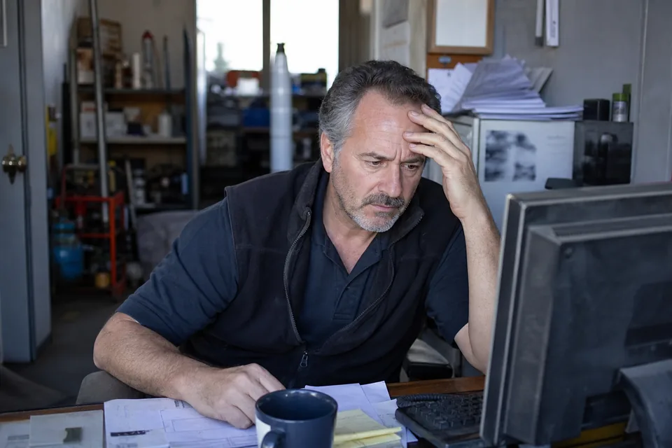 Small business owner in a workshop office looking at his computer after his website went offline
